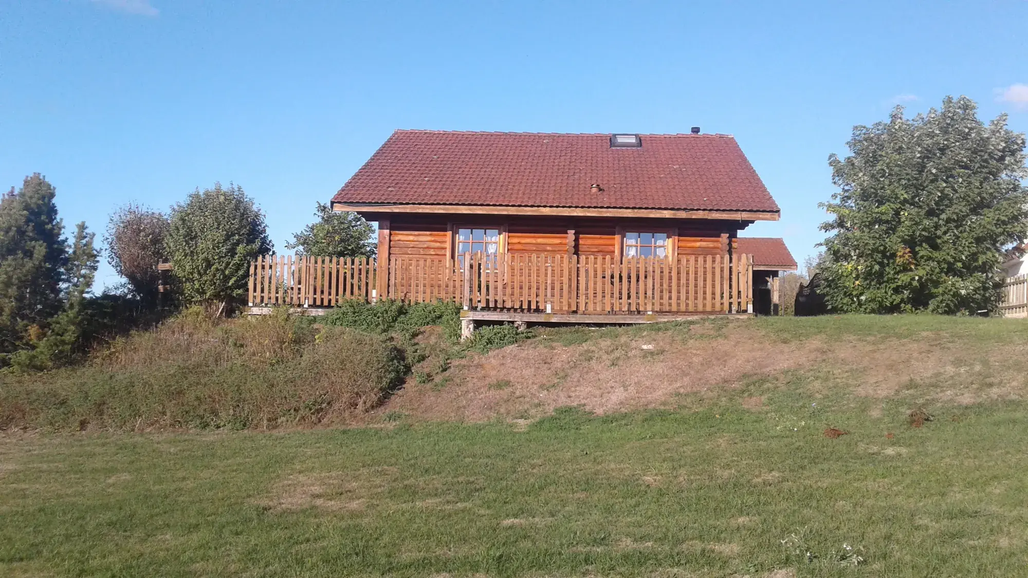 Le Chalet Peter et sa terrasse en bois sous le ciel bleu d'octobre