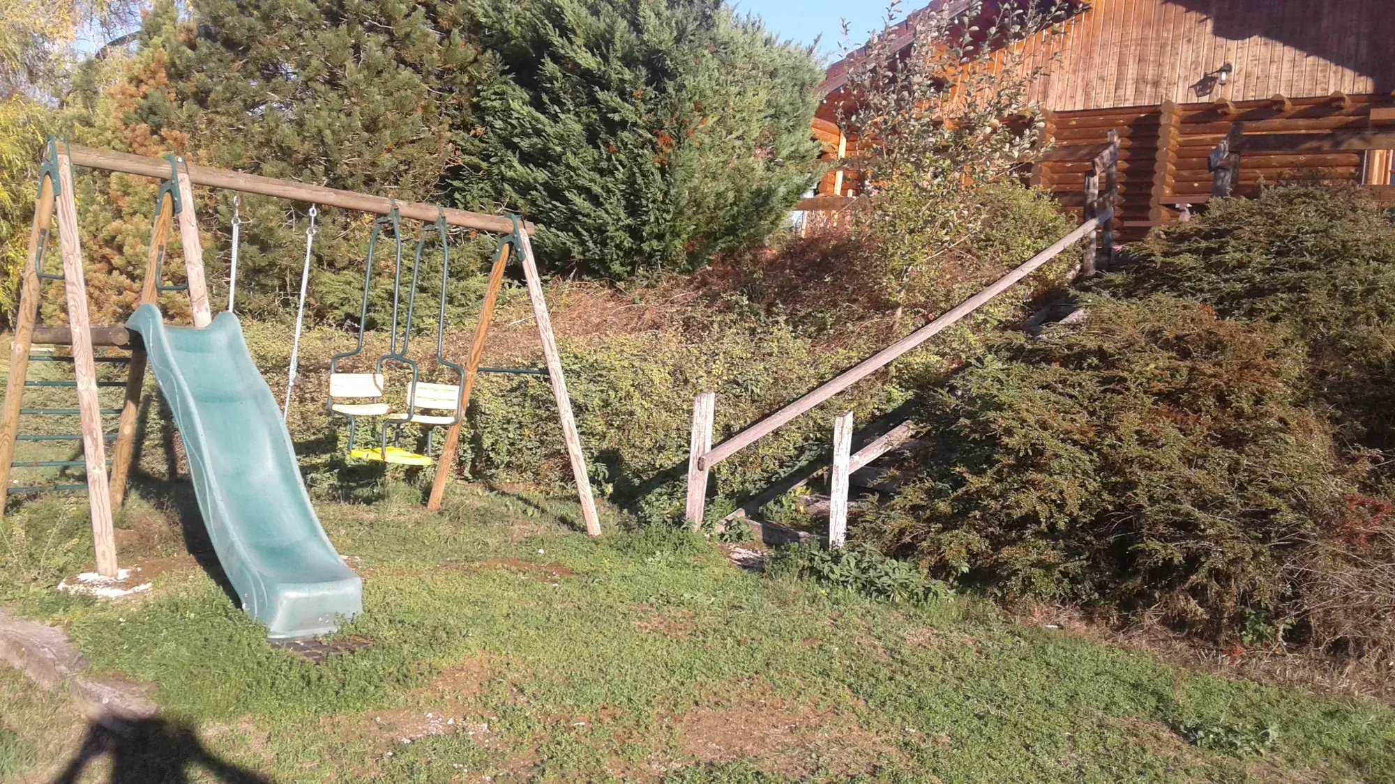 L'aire de jeux des chalets : balançoires et toboggan sur la pelouse