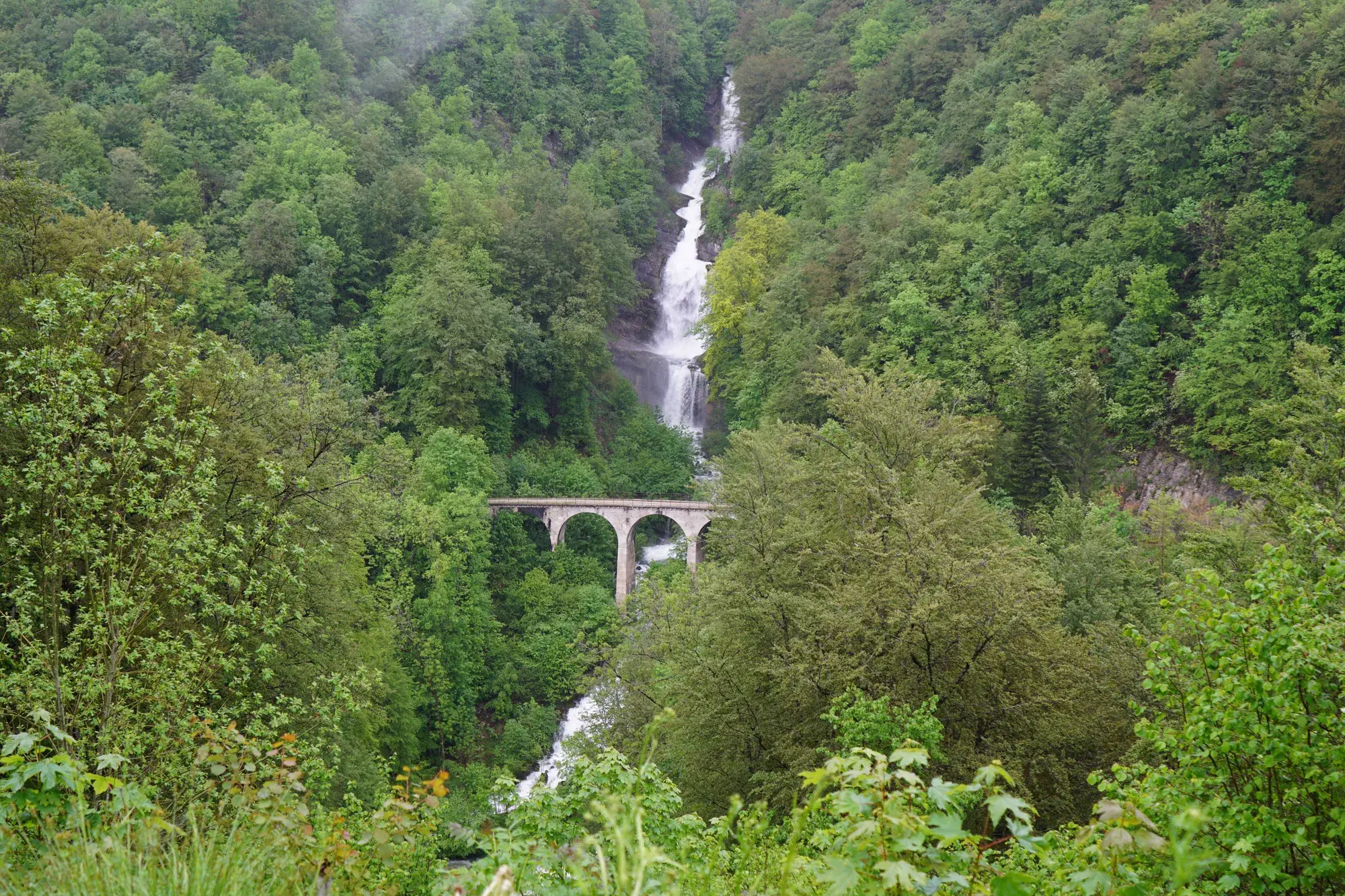 Cascade et viaduc au creux d'une vallée boisée du Jura